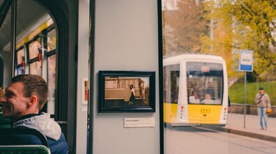 Всередині трамвайного вагона висить фотокартина в чорній рамці, на якій зображена дівчина на підніжжі ретро-трамвая. Ліворуч від неї сидить пасажир, а праворуч крізь вікно ззовні видно зупинку, чоловіка та інший жовтий трамвай