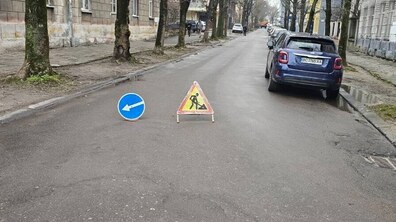 частина вулиці Олени Степанівни, де на проїзній частині дороги стоїть знак ремонтні роботи, та знак, який вказує напрямок обїзду
