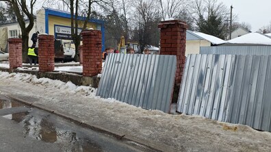процес демонтажу паркану на вул. Повітряній у Львові. Зняті металеві листи, стоять коло цегляних стовпців. Позаду комунальні служби продовжують демонтаж паркану з технікою