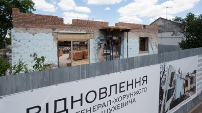 Будівля музею під час відновлення. Роботи тривають. На передньому плані великий банер із надписом про відновлення музею.