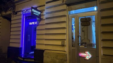 фасад будинку на одній з вулиць Львова з вивісками та неоновим освітленням магазинів