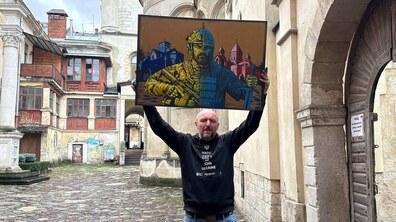 У дворику біля Вірменського катедрального собору у Львові художник Андрій Єрмоленко тримає над головою картину. Наполотні зображено постать, розділену навпіл: зліва — сучасний український захисник вірменського походження у військовому спорядженні, справа - давній вірменський воїн в обладунках. На тлі - два собори. Поруч видно старовинну аркову браму, дерев'яну галерею та брукований двір.