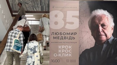 Праворуч видніється банер події з фотографією Любомира Медвідя. Ліворуч люди підіймаються сходами до виставки