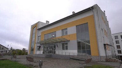 Двоповерхова будівля народного дому в Сокільниках з фасадом сірого та жовтого кольорів. Перед нею є лавки та забрукована площа.