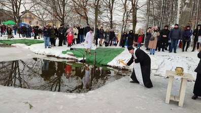 Водохреща на озері в Горіхову Гаю - багато людей стоять довкола, а священник у традиційній святковій рясі здійснює освячення води
