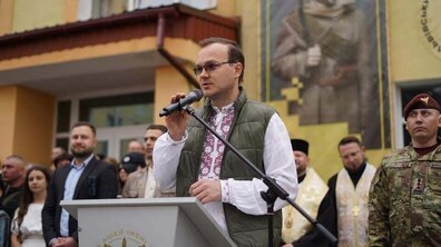 Перший заступник міського голови Львова Андрій Москаленко у вишиванці виступає з мікрофоном за трибуною. На другому плані стоять інші люди, серед яких військові та священнослужителі