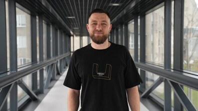 Морпіх та оборонець Маріуполя Андрій Ординський стоїть у центрі UNBROKEN та усміхається; він одягнений у футболку чорного кольору на якій є лого та напис UNBROKEN