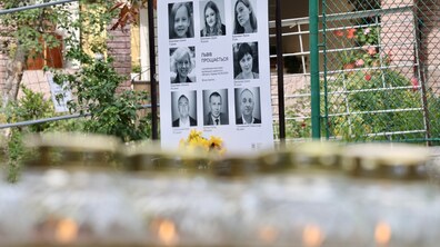 На подвір’ї стоїть меморіальний стенд із фотографіями загиблих внаслідок ворожої атаки на Львів 4 вересня 2024 року. Перед стендом лежать квіти, а на передньому плані видно запалені лампадки