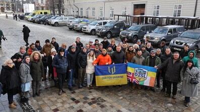 військові, представники міжнародних гуманітарних організацій та Львівської міської ради на фоні переданих автівок