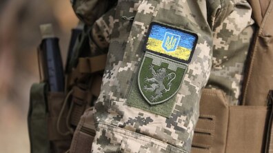 Рука військового з нарукавним знаком Державний Прапор України та нарукавним знаком військової частини