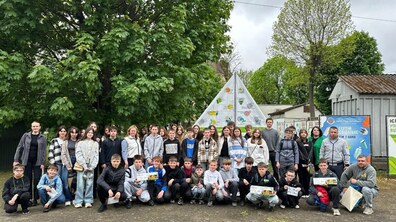 Група дітей на території комунального підприємства «ТФ Львівспецкомунтранс». Вони знаходяться біля стенду з написом «Сортуй відповідально» та екологічними піктограмами. На другому плані – зелені дерева