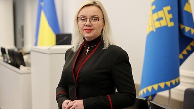 Керівниця ЛКП «Львівелектротранс» Ірина Іванишин у великій сесійній залі. На другому плані видно прапори України та Львова.