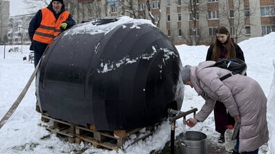 Мешканці набирають воду із великої чорної ємності для питної води. Поруч стоїть працівник водоканалу