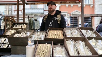Ветеран стоїть за яткою на ярмарку у Львові. На ятці розкладені його вироби