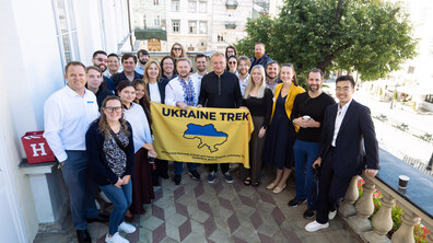Спільне фото: учасники міжнародної делегації спільно з мером Львова Андрієм Садовим на балконі міської Ратуші. Вони тримають жовто-блакитний прапор із написом «UKRAINE TREK» та картою України. Всі усміхаються й дивляться в камеру.