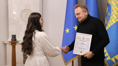 Міський голова Андрій Садовий тисне руку учениці, що здобула премію та вручає їй сертифікат.