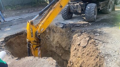 Велике провалля посеред проїзної частини на вул. Героїв УПА. У розритті працює жовтий екскаватор, ковш якого опущений глибоко в яму.