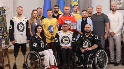 Групове фото у кабінеті міського голови Львова на тлі прапорів України та ЄС. На передньому плані сидять троє спортсменів у кріслах колісних, а ліворуч стоїть чоловік із протезами ніг — усі вони вдягнені у чорно-білу хокейну форму. У центрі другого ряду стоїть мер Львова Андрій Садовий у помаранчевому джерсі, який тримає в руках пам'ятну нагороду.