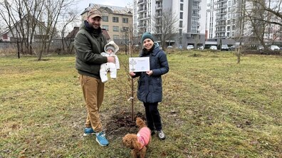 Тато тримає на руках маленького сина Устимка. В руках мами подяка від управління екології та природних ресурсів за участь у акції. Сім’я стоїть біля висадженого дерева. Поруч з ними невеликий рудий собака