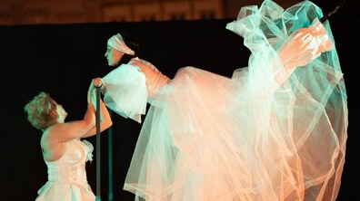 Вивіска театру «Воскресіння» та актори в сценічних костюмах на тлі міської забудови.