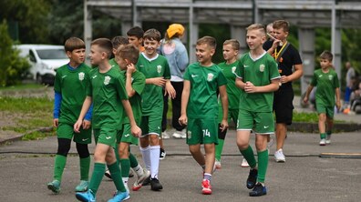 Діти у зеленій футбольній формі йдуть вулицею.