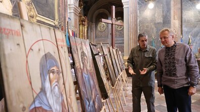 На фото ліворуч зображено ікони з проєкту «Ікони на якщиках з-під набоїв». Праворуч - міський голова та один із представників проєкту розглядають його та діляться думками.