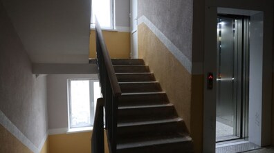 cходи між поверхами у житловому будинку, поруч ліфт з відчиненими дверима