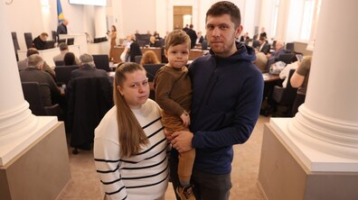сім'я Марка Гладиша. Мама Анастасія і тато Роман, який тримає хлопчика на руках. На задньому фоні - сесійна зала міської ради.