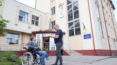Двоє чоловіків спілкуються на фоні будівлі центру реабілітації «Галичина»
