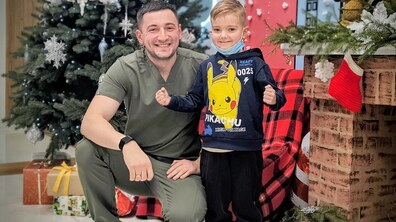 Пацієнт – Артурчик поряд з Максимом Овечко, керівником Центру трансплантології Першого медоб’єднання Львова; на фоні прикрашена ялинка та різдвяні декорації