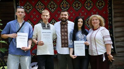 Начальник відділу професійно-технічної освіти Львова Богдан Іванусь та учасники змагань роблять спільне фото. Усі вдягнені у вишиванки, а позаду видно традиційну сільську українську хату.