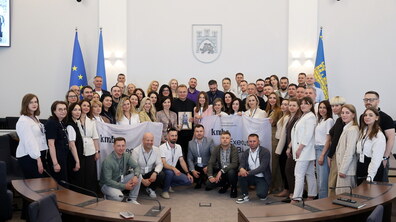 Учасники навчального туру «Києво-Могилянської бізнес-школи» (kmbs) разом із міським головою Львова Андрієм Садовим після зустрічі у Львівській міській раді. Група позує у великій сесійній залі на тлі герба Львова та прапорів України, Європейського Союзу і міста. Декілька учасників тримають прапори kmbs Executive MBA, а міський голова книгу — пам’ятний подарунок, вручений під час зустрічі.