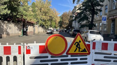 Вул. Залізнична перекрита для руху через ремонтні роботи. На передньому плані дорогу повністю перегороджує біло-червоне пластикове огородження. На ньому встановлено два знаки: круглий «Рух заборонено» та трикутний «Дорожні роботи».