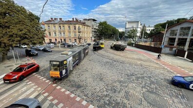 Перехрестя вулиць Сахарова, Вітовського та Нечуя-Левицького, поруч із пл. Лема у Львові. Бруковану площу перетинають трамвайні колії, якими рухається трамвай. Довкола їдуть автомобілі, а на тлі видно історичні кам’яниці та дерева.