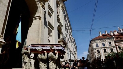 З храму виносять домовину з військовослужбовцем. Біля церкви зібралось багато людей, які моляться