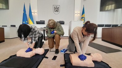 Дві учасниці навчань відпрацьовують на манекені непрямий масаж серця під керівництвом інструкторки.