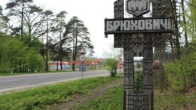 дорога на в’їзді до Брюховичів. Збоку дерев’яний знак з назвою населеного пункту