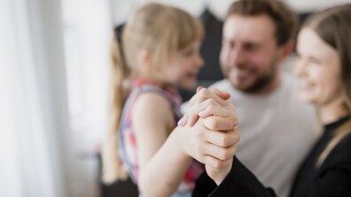 Жінка тримає за руку дівчинку, біля них стоїть чоловік: усі усміхнені