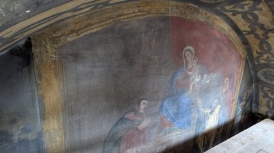 Старовинний потемнілий настінний релігійний розпис із зображенням святих постатей у червоному і синьому вбранні. Марія на руках тримає немовля Ісуса