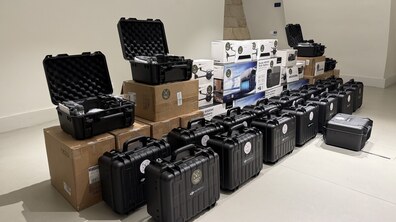 Дрони, планшети і зарядні станції у коробках та спеціальних кейсах стоять у приміщенні.