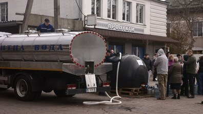 люди набирають воду у ємності. Поруч стоїть водовоз.