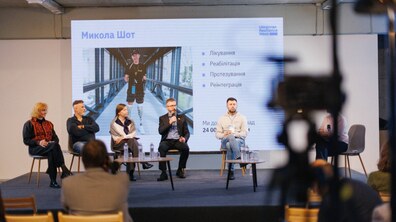 На сцені триває панельна дискусія в межах Ukrainian Resilience Week. На екрані позаду — фото Миколи Шота на протезах та інформація про лікування, реабілітацію, протезування і реінтеграцію.