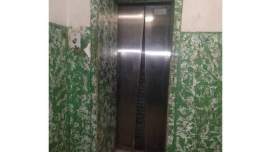 зачинені металеві двері ліфта зі щілиною посередині, за якою видно темну шахту, розташовані у під’їзді зі зеленими стінами.