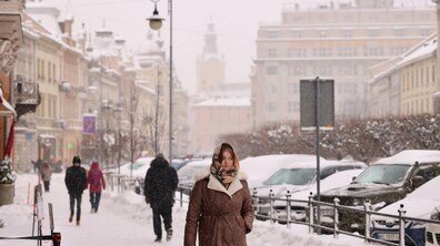 Засніжений Львів. По вулиці йдуть люди. Поруч припарковані машини.