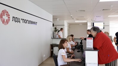 Оновлена сучасна реєстратура лікувально-діагностичного центру «Погулянка». Працівники за стійкою обслуговують відвідувачів. На стіні вгорі розміщено логотип і напис «ЛДЦ 
