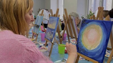 під час майстеркласу жінка малює картину акварельними фарбами