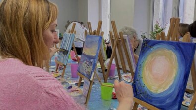 Під час майстерки жінка малює картину акварельними фарбами