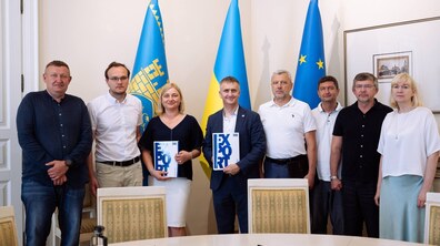 Представники Львівської міської ради, Укргазбанку, Укрексімбанку та депутати ЛМР, позують на фоні прапорів.