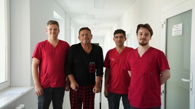 Спільне фото: у світлому лікарняному холі стоять пацієнт Юрій та лікарі, які його лікували. Усі дивляться в камеру й усміхаються.