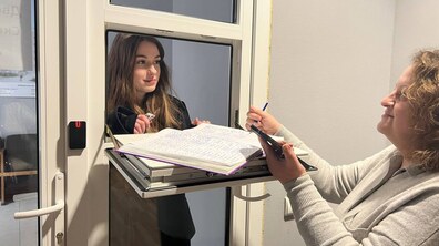 Працівниця Бюро знахідок зустрічає відвідувачку і через віконце у дверях дає їй журнал та ручку для записів